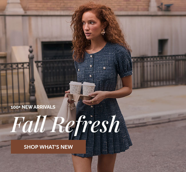 Young woman in a short, dark blue, textured dress with puff sleeves and pearl buttons.