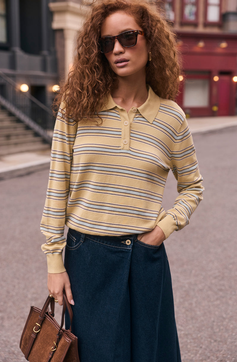 Beige and yellow striped long-sleeve polo shirt with buttons, paired with wide-leg jeans.