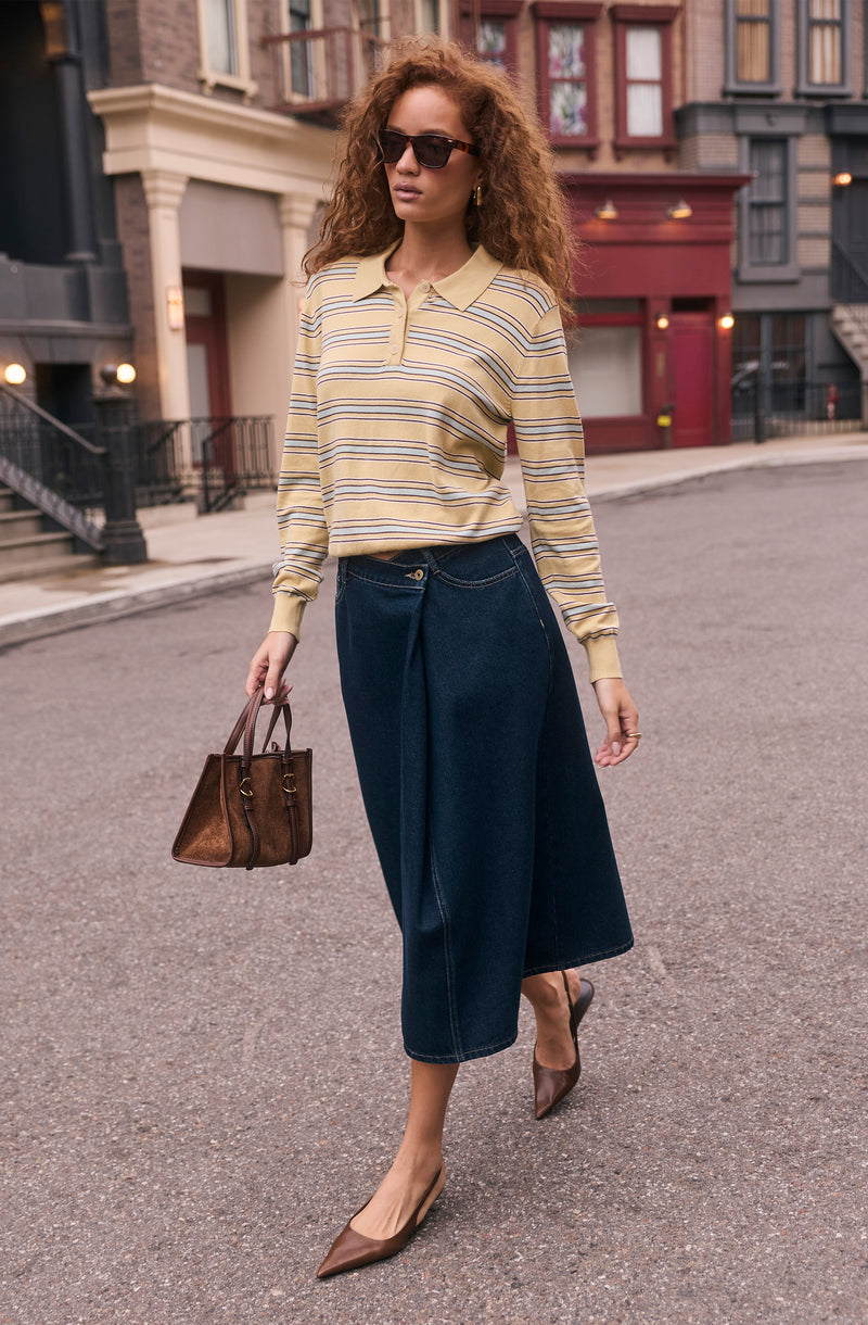 Woman wearing a yellow striped long-sleeve polo shirt, navy wide-leg jeans, brown pointed heels, and sunglasses.