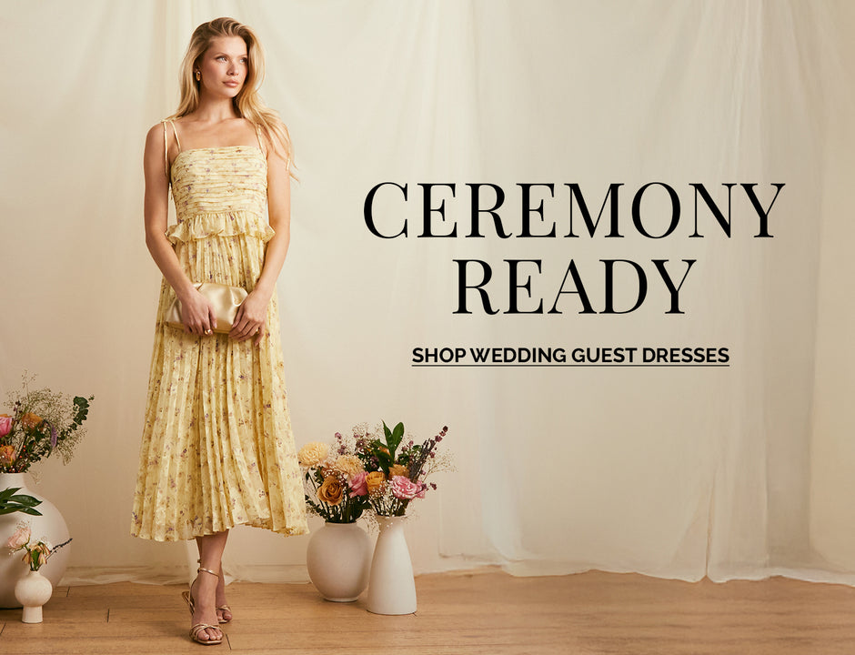 Woman in a yellow, strapless, tiered dress with floral pattern and ruffled top, holding a clutch.