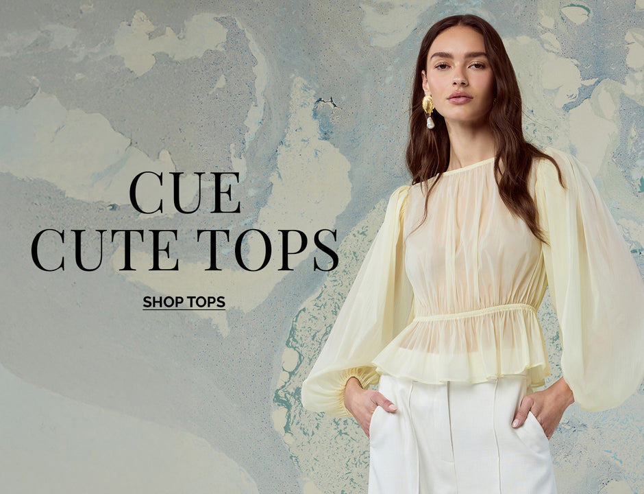 Woman wearing cream colored, sheer, puff-sleeve blouse with ruffled hem and high waist pants.