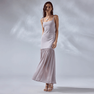 Woman in a long, sleeveless white dress with a fitted bodice and a flowy, pleated bottom.