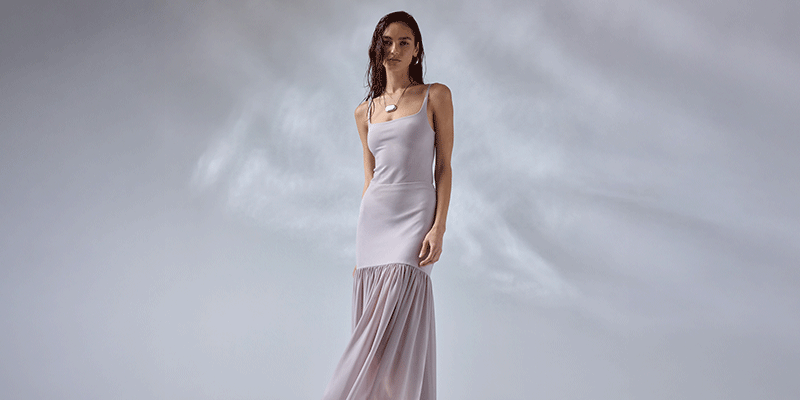 Woman in a long, white, sleeveless dress with a fitted bodice and a flowing skirt.