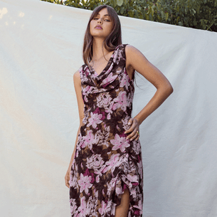 Woman in sleeveless floral dress with pink and purple flowers, ruffled hem, and cowl neckline.
