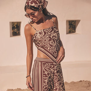 Woman wearing a patterned sleeveless top and matching wide-leg pants with vertical stripes.
