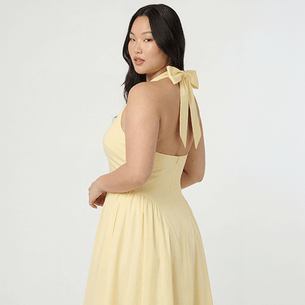 Woman in a light yellow halter dress with large bow on the back.