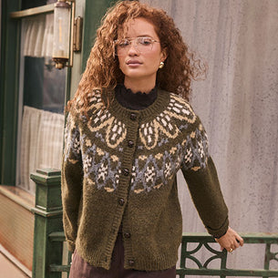 Woman wearing a green cardigan with a large, intricate beige, purple, and blue pattern on the yoke.