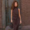 Woman wearing a sleeveless, high-neck dark brown top and matching pants with a tied waist.