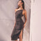 Woman wearing a dark, one-shoulder, sleeveless dress with a slit on the side.