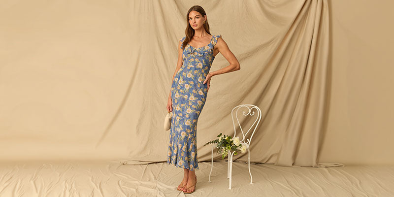 Woman wearing a blue floral dress with cap sleeves and a fitted silhouette.