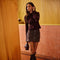 Woman in a dark burgundy sweater and brown button-front skirt with large pockets.