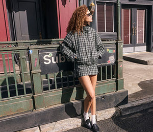 Person wearing a black and white checked oversized jacket and matching shorts.