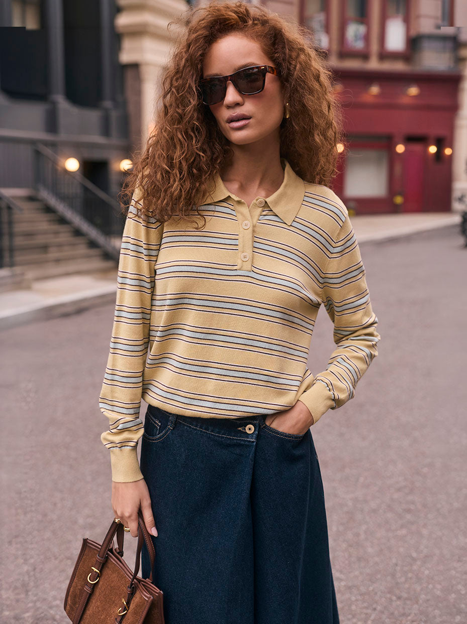 Woman wearing a yellow and blue striped long-sleeve polo shirt, dark wide-leg jeans, and sunglasses.
