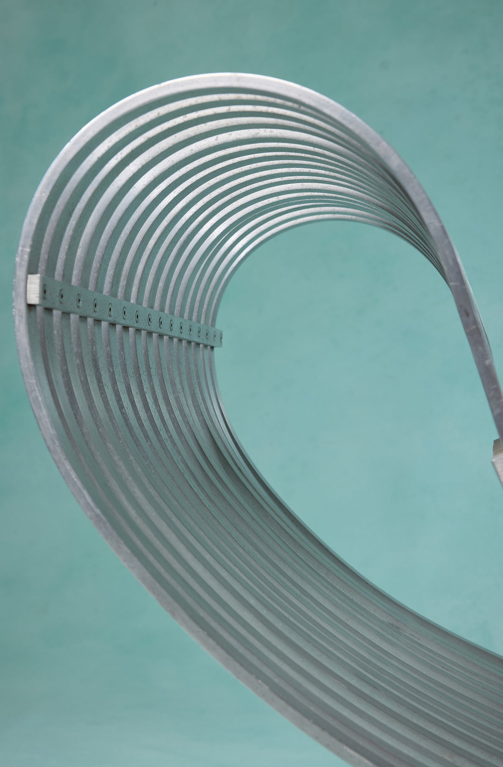 Silver metallic ladder with evenly spaced rungs, curved against a greenish background.