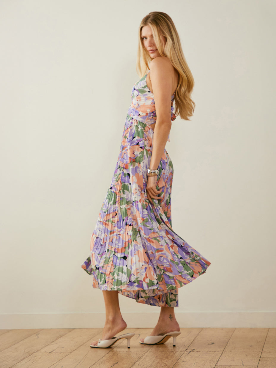 Woman wearing a colorful, floral maxi dress with spaghetti straps and a pleated skirt.