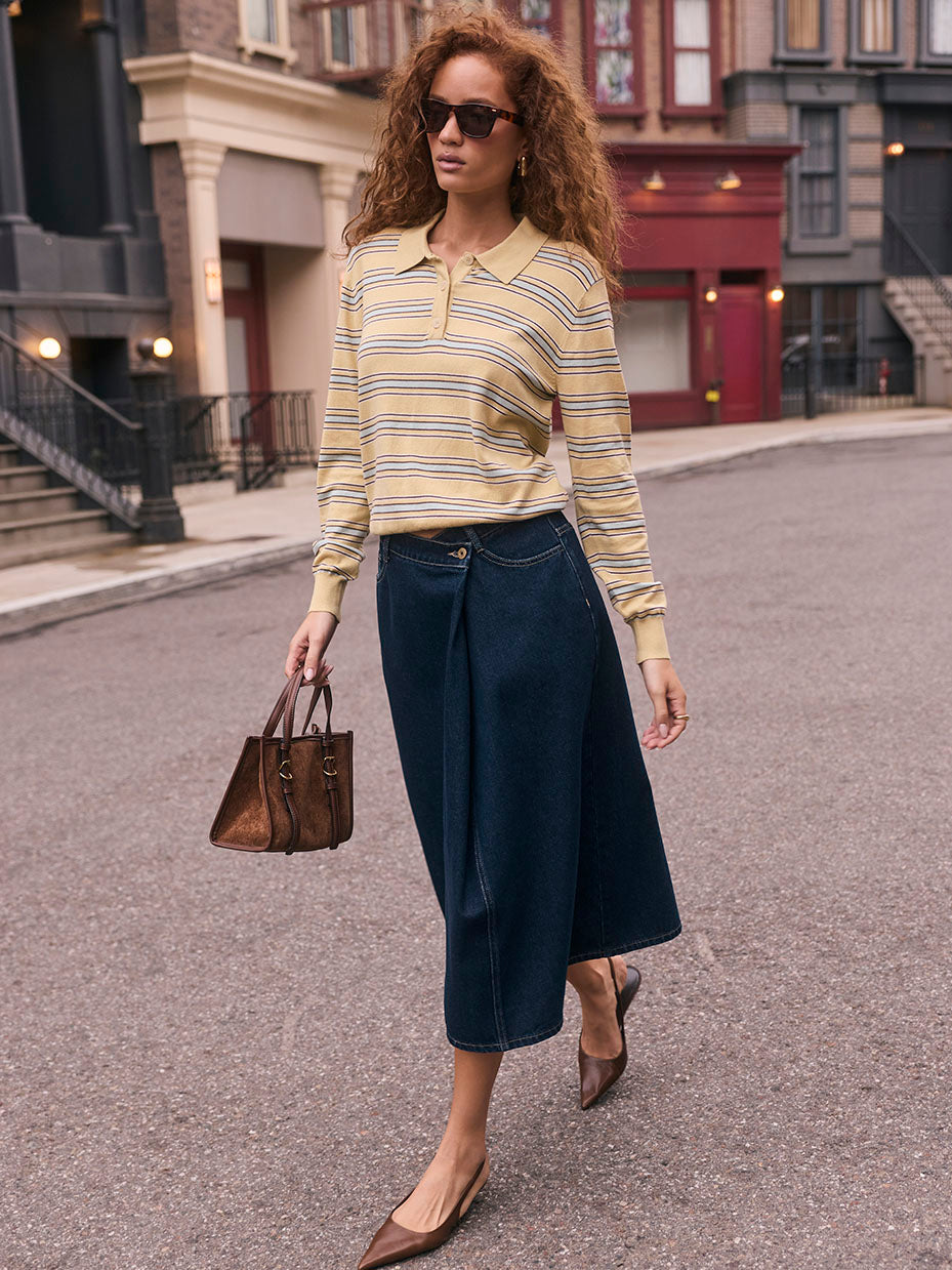 Woman wearing a yellow striped long-sleeve polo shirt, wide-leg dark blue jeans, brown pointed heels, sunglasses, and carrying a brown handbag.