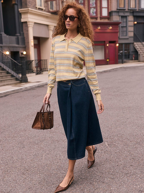 Woman wearing a yellow striped long-sleeve polo shirt, wide-leg dark blue jeans, brown pointed heels, sunglasses, and carrying a brown handbag.