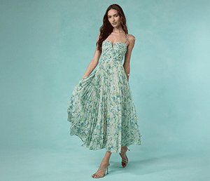 Woman in a green floral strapless dress with a flowy skirt and nude heeled shoes.