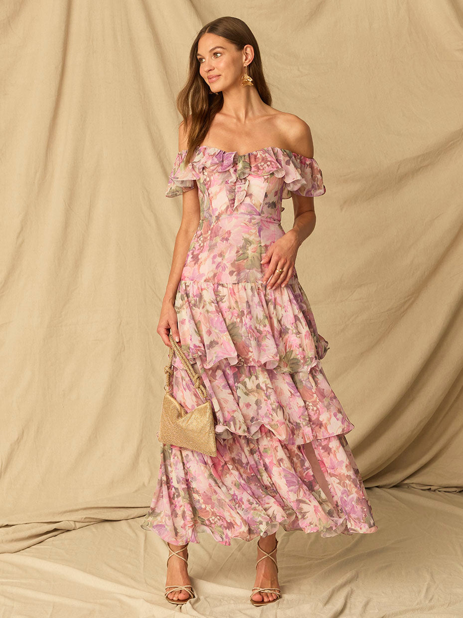 Woman wearing a pink floral off-shoulder dress with ruffles and tiered skirt.