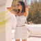 Woman wearing a white sleeveless lace crop top and a white lace tiered skirt.