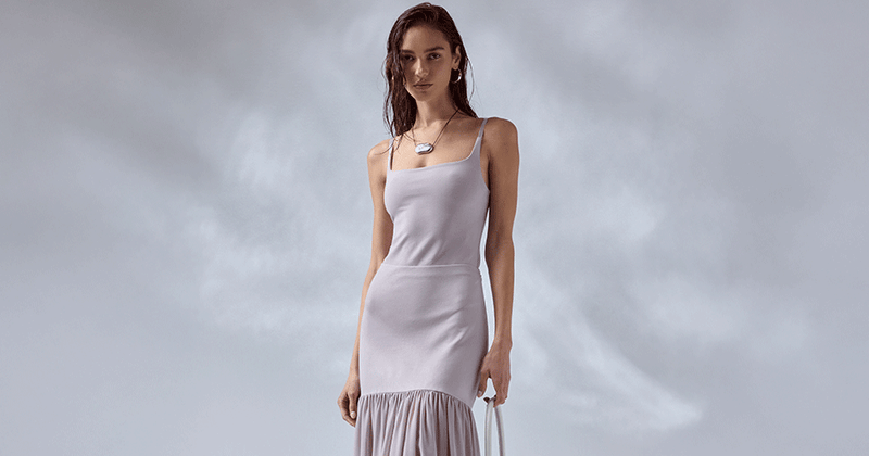 Woman wearing a white sleeveless dress with spaghetti straps and a ruffled hem.